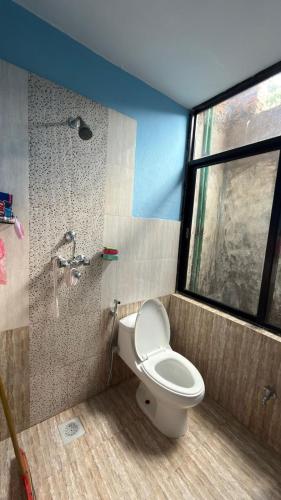 a bathroom with a toilet and a window and a shower at Satikhel StayInn in Pharping
