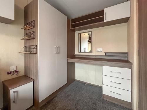 a small kitchen with white cabinets and a mirror at The Fern caravan 17 in Angus