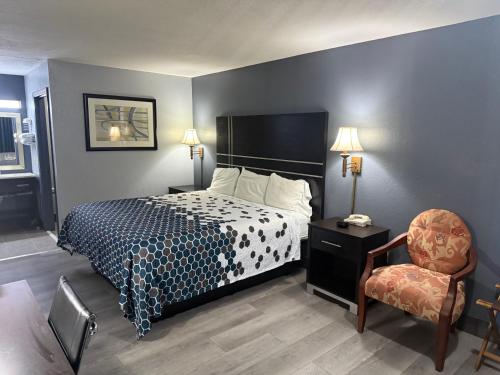 a hotel room with a bed and a chair at Western Motel - Jesup in Jesup