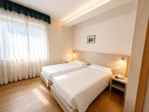 a hotel room with two beds and a window at Hotel International in Tarvisio
