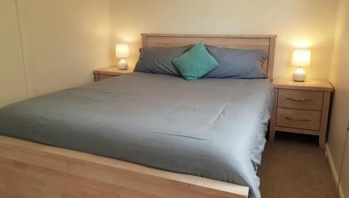 a bedroom with a bed with blue pillows and two night stands at Beach Break in Tathra