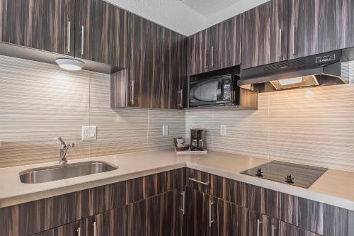 a kitchen with wooden cabinets and a sink and a microwave at Comfort Inn Trenton in Trenton