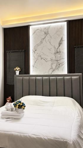 a bedroom with a white bed with a marble wall at Norden Barn B&B in Chiang Mai