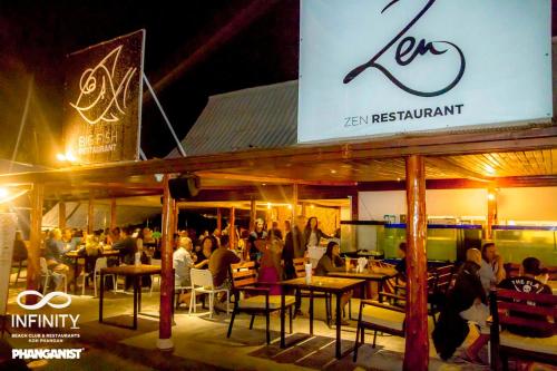 a group of people sitting in a restaurant at night at Infinity Beach Club Resort & Hostel Koh Phangan in Baan Tai