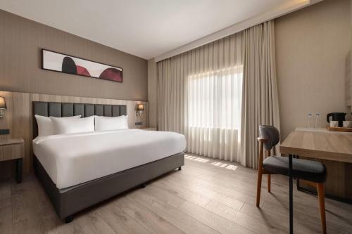 a hotel room with a large bed and a desk at Ramada Encore by Wyndham Midyat in Midyat