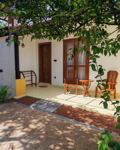 a porch of a house with two chairs and a door at Mogra Bliss in Matara