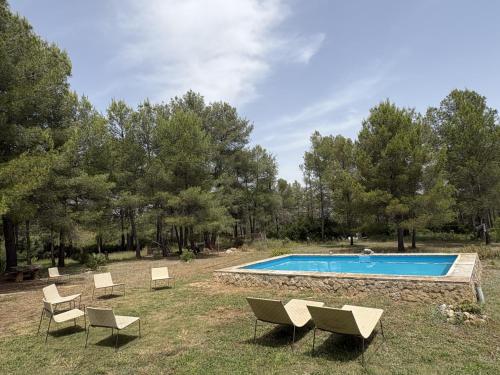 a swimming pool in a field with chairs around it at Refugio de Montaña "El Caroche" Alojamiento entero in Enguera