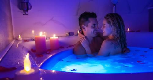 a man and a woman sitting in a bathtub with candles at Suite Romantique La Charmante in Villersexel