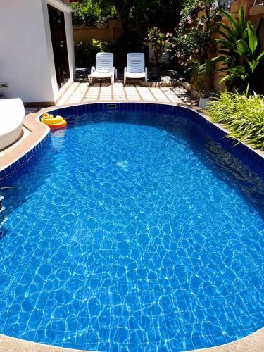 a large blue swimming pool with two chairs in a yard at Massarossa Luxury European Style Private Pool Villa in Pattaya