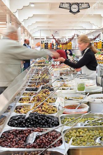un groupe de personnes debout dans une épicerie vendant des fruits dans l'établissement Suquet26, à Cannes