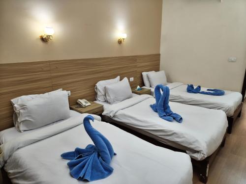 three beds in a hotel room with blue bows on them at S S Luxor Hotel in Luxor