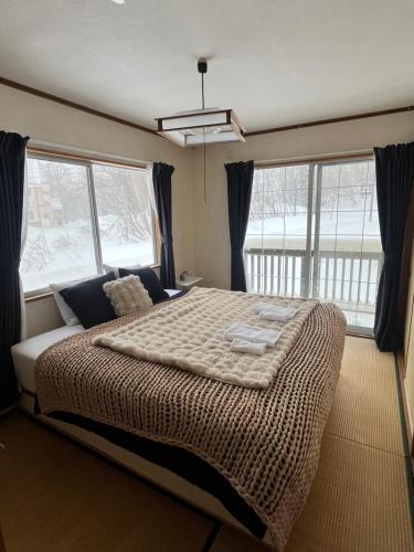 a bedroom with a large bed with a large window at Corduroy Ski Lodge Madarao Tangram in Shinano