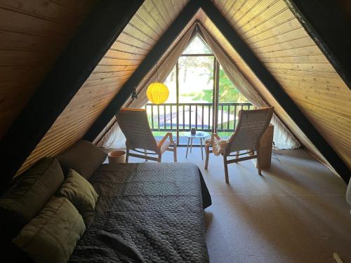 a bedroom with a bed and two chairs and a table at Authentic wooden summer house in Øster Hurup