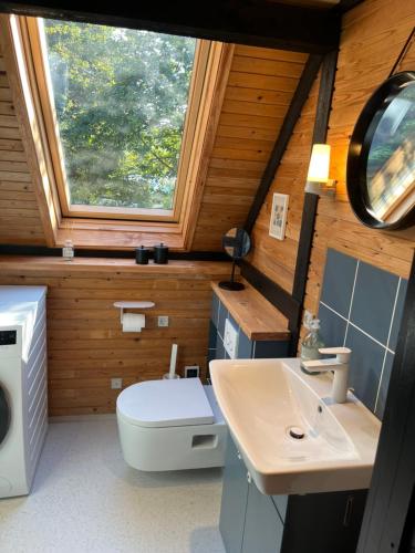 a bathroom with a sink and a toilet and a window at Authentic wooden summer house in Øster Hurup