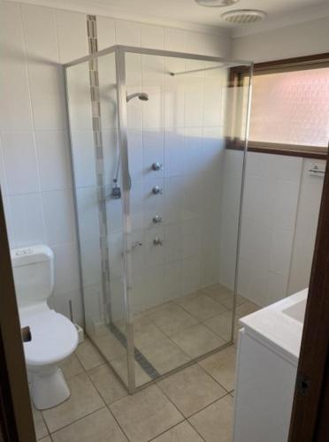 a bathroom with a shower and a toilet at Edna's Retreat in Tathra