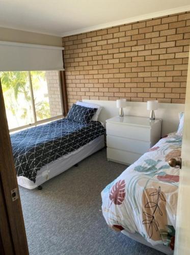 a bedroom with two beds and a brick wall at Edna's Retreat in Tathra