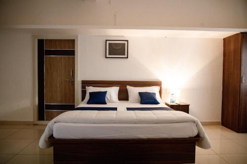 a bedroom with a large bed with blue pillows at Sushi Greens Suites in Dāvangere