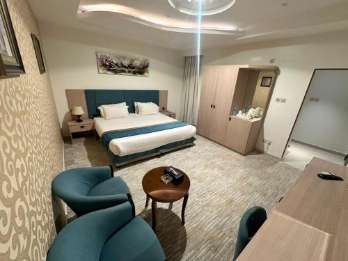 a hotel room with a bed and blue chairs at فندق روز أوسيس - Roz Oasis Hotel in Najran