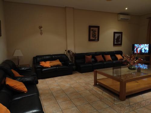 a living room with black leather couches and a coffee table at HOTEL RURAL HIDALGO in Torreperogil