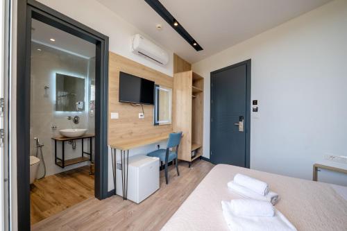 a bedroom with a bed and a desk and a bathroom at F&J Hotel in Sarandë