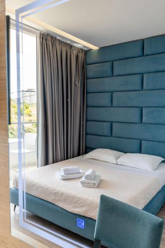 a bedroom with a bed with a blue headboard at F&J Hotel in Sarandë