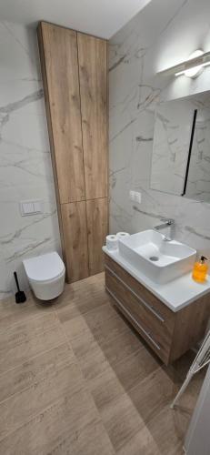 a bathroom with a sink and a toilet and a mirror at White Pearls Apartaments Dąbki in Dąbki
