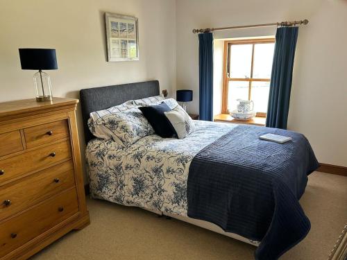 a bedroom with a bed and a dresser and a window at Heigh Farmhouse in Lancaster