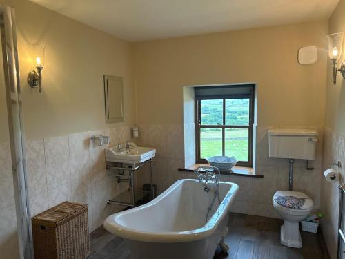 a bathroom with a tub and a sink and a toilet at Heigh Farmhouse in Lancaster
