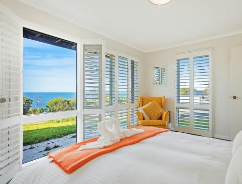 a bedroom with a bed and a large window at Whale Stay in Tathra