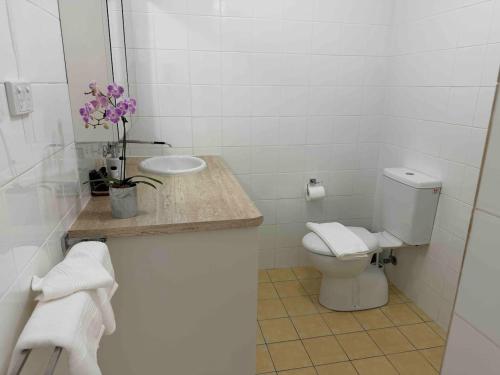 a white bathroom with a toilet and a sink at Whale Stay in Tathra