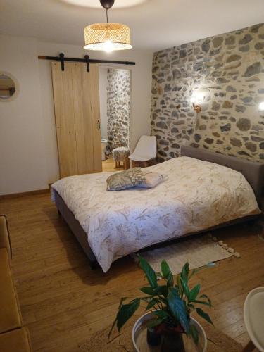 a bedroom with a large bed and a stone wall at L étable au naturel in Mauriac