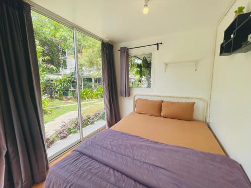 a bedroom with a bed and a large window at 3199 Cafe' Latya & Bed in Ban Lum Makok