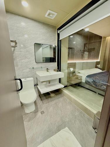 a bathroom with a toilet and a sink and a bed at Skyport Hotel in Manila