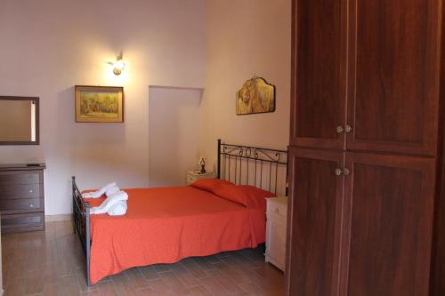 a bedroom with a bed with red sheets and a wooden cabinet at B&B La Taverna in Campodimele