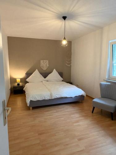 a bedroom with a white bed and a chair at WeLiving Apartments in Weinheim