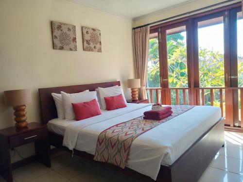 a bedroom with a large bed and a balcony at Sekuta Condo Suites in Sanur