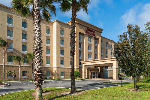 a hotel with palm trees in front of a building at Hampton Inn & Suites - DeLand in De Land