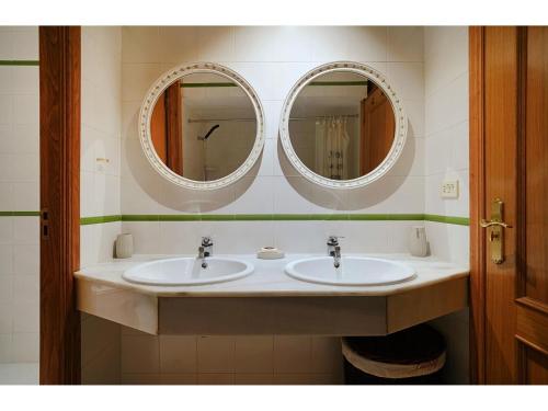 two sinks in a bathroom with two mirrors at GALIHOST - Casa Chouba, frente a la playa in Sanxenxo