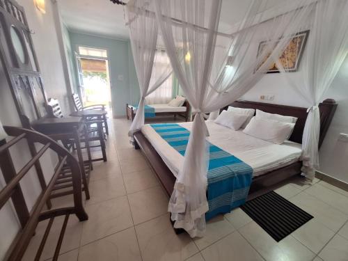 a bedroom with a bed with a mosquito net at Ocean Haven in Induruwa