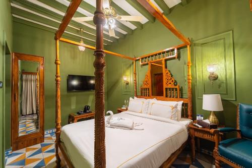 a bedroom with a canopy bed and a blue chair at Hotel Palais De Versailles in Pondicherry