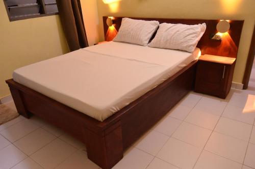 a bed with white sheets and pillows on it at Résidence Saint Gall-H in Ouidah