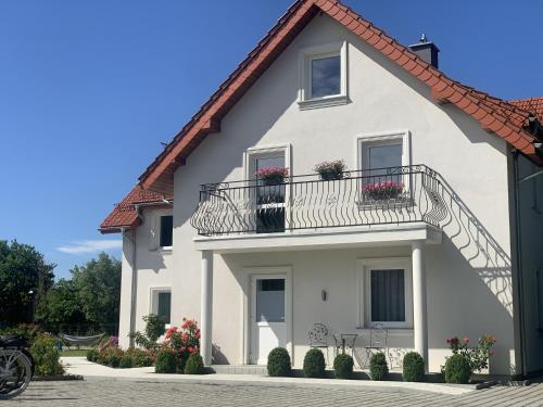 a white house with a balcony and flowers at Willa Róż in Rusinowo