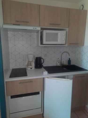 a kitchen with a sink and a microwave at Studio 4 pers / terrasse / espace aquatique in Talmont
