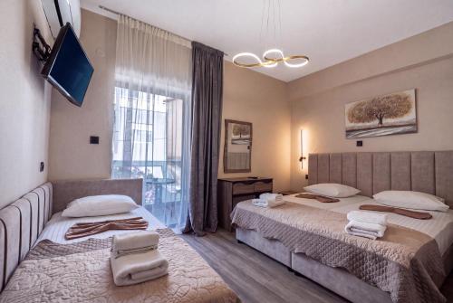 ein Schlafzimmer mit zwei Betten und einem großen Fenster in der Unterkunft Hotel Petunia in Neos Marmaras