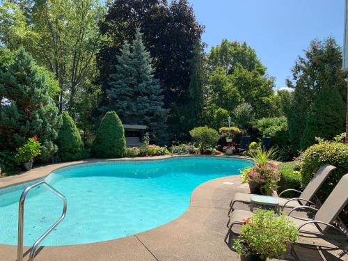 a swimming pool in a yard with chairs and trees at Bruce Manor in Niagara-on-the-Lake