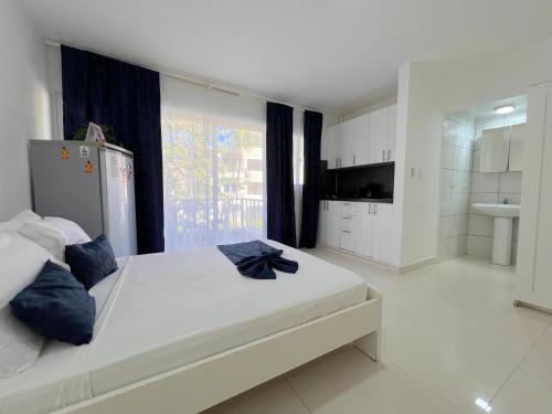 a white bedroom with a large bed and a bathroom at DELUXE STUDIOS with POOL VIEW and Wi-Fi at PLAYA LOS CORALLES in Punta Cana