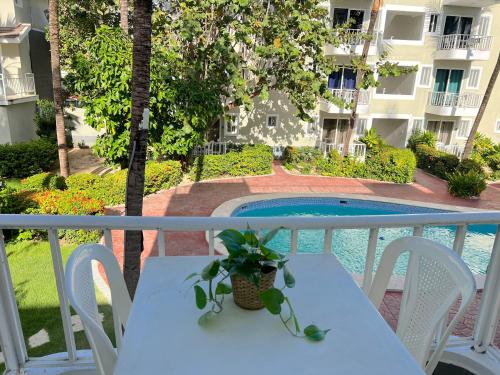 a table and chairs on a balcony with a pool at DELUXE STUDIOS with POOL VIEW and Wi-Fi at PLAYA LOS CORALLES in Punta Cana
