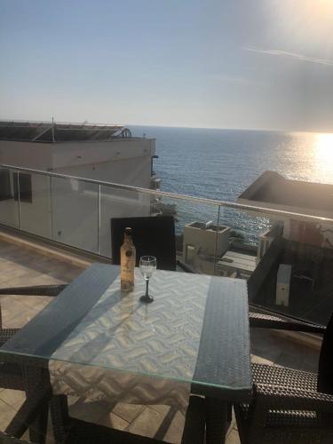 a table with a wine bottle and a glass on a balcony at Pogled na more in Pečurice
