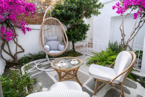 a patio with two chairs and a table and flowers at Neoclassical Mansion in Andros Town by Explore Andros in Andros