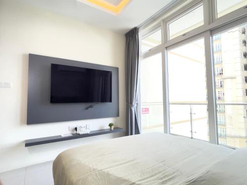 a bedroom with a tv on a wall with a bed at Blue Cove Riverine Diamond Kuching in Kuching